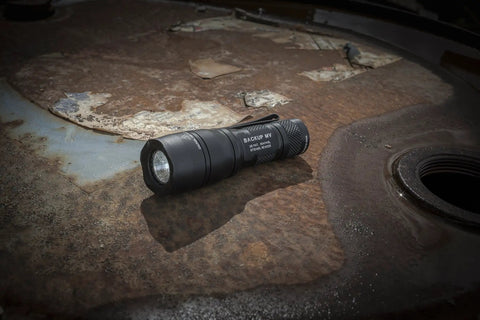 Dual Output LED Backup Flashlight With MaxVision Beam Technology For Everyday Carry Compact Pocket Light on rustic metal surface