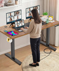 Farexon Electric Standing Desk Adjustable Height Black Brown Wood Grain Surface With Power Outlets, Wheels, And Mouse Pad for dual monitor setup in home office.