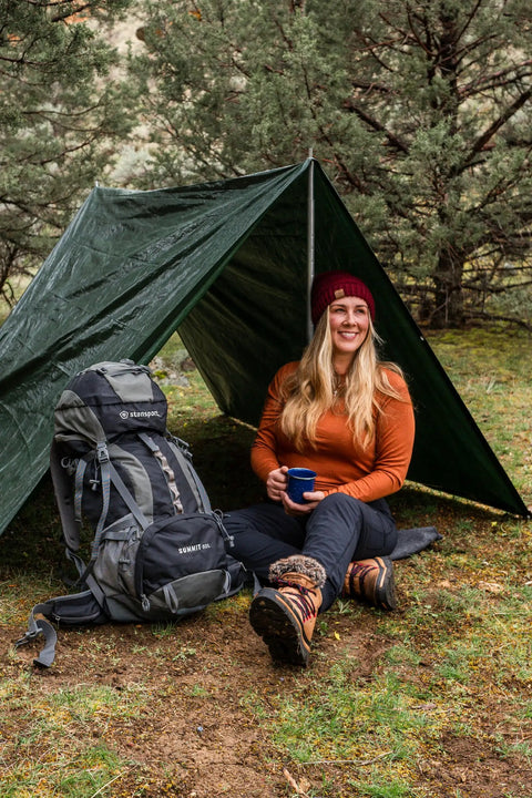 Woman sitting with Medium Duty Ripstop Camping Tarp 6 By 8 Feet Waterproof Cover Dark Green 5 Mil Thick With Reinforced Grommets