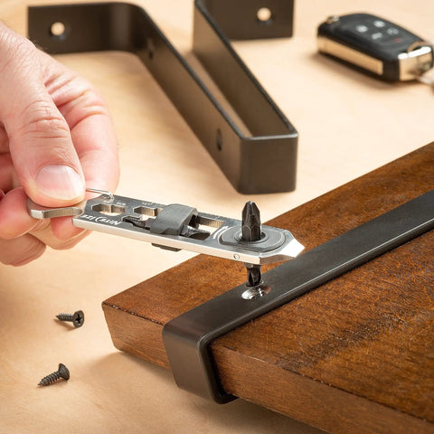 Person using DoohicKey Ratchet Key Tool Keychain Friendly Pocket Multitool for tightening screws on a wooden board