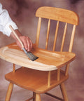 Person applying Clear SealCoat Universal Sanding Sealer for Interior Wood and Floors to wooden high chair