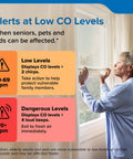 Woman checking CO detector readings by the window, ensuring safety with Top Shelf Carbon Monoxide Detector With Ten Year Battery Backup And Loud Eighty Five Decibel Alert For Worry Free Home Safety Monitoring And Quick Low Level Hazard Scan Shield.