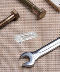 10-Pack Plastic Shelf Pegs For Cabinets And Shelves, Durable ABS Material shown next to bolts and wrench on textured surface