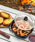 12 Inch Cast Iron Skillet With Lid Pre Seasoned Chef Pan For Indoor And Outdoor Cooking on picnic table by campfire