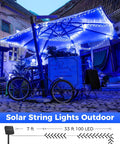 Outdoor seating area lit by solar string lights under an umbrella in a cobblestone courtyard.