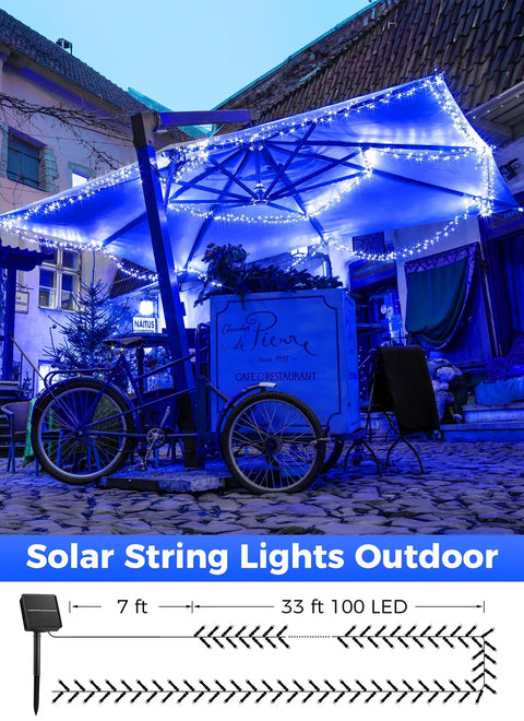 Outdoor seating area lit by solar string lights under an umbrella in a cobblestone courtyard.