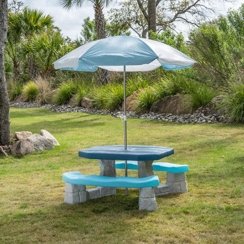 Sun And Fun Picnic Table With Umbrella For Indoor And Outdoor Use Toddler Sized Table With Five Foot Shade Canopy That Blocks UVA And UVB Rays For Safe Chill Backyard Fun on grass.