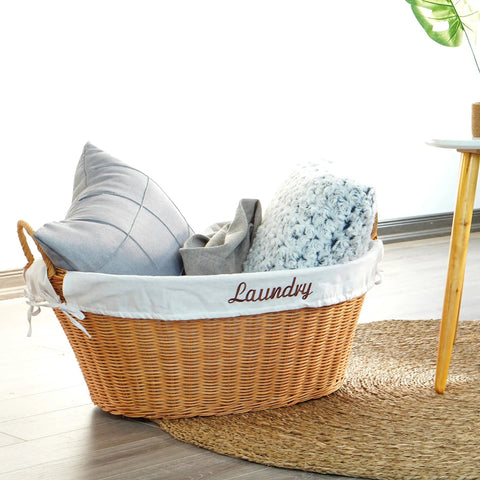 Rattan Laundry Basket With Easy Carry Handles And Removable White Cotton Liner, filled with pillows, on a woven rug.