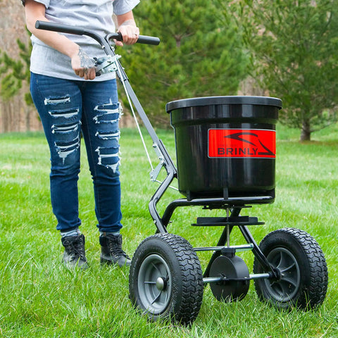Person using 50 Lb Capacity Push Broadcast Spreader For Lawns And Gardens, Easy Push Handle, Durable Heavy Duty Frame, Model P20-500BH