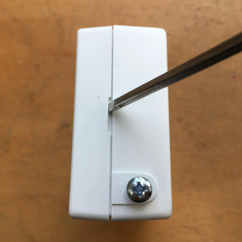Installing Easy Install Door Alarm With 16x12 Foot Detection Area And 70dB Alert using a screwdriver on brown surface.