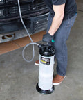 Person using Manual Fluid Extractor Pump for Oil Change and Transmission Fluid, 8L Capacity, in a garage next to a vehicle.