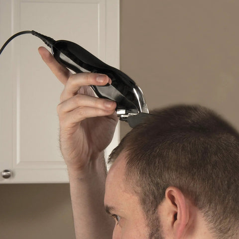 Person using Deluxe Corded Clipper Pro Hair And Trim Kit with corded clipper for precise haircutting at home