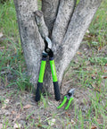 Limb And Branch Pruner Tool Set with 15in lopper and 8in pruner, steel blades, green handles, in front of a tree base.