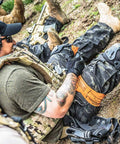 Orange Tourniquet For Emergency First Aid And Tactical Use With Stretch Wrap And Tuck Design For Massive Hemorrhage Control In Prehospital Care Made In The USA applied on leg in field training