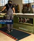 Anti Fatigue Standing Mat For Work with orange border in an industrial workshop, reducing leg and back pain, 20 by 32 inches