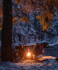 Two people enjoying Smokeless Propane Fire Pit 19 Inch Portable Firebowl 58K BTU With Self Igniter Cover in a snowy forest