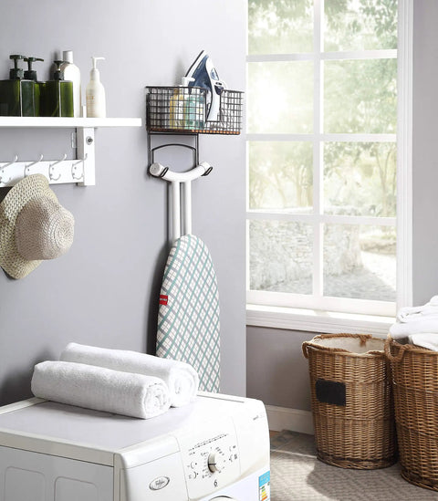 Metal Over The Door Or Wall Mount Ironing Board Holder With Large Storage Basket in a laundry room setting