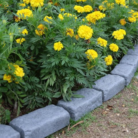 Realistic Faux Stone Landscape Edging Kit With 24 Bricks, 15.5 Ft Total bordering yellow flowers in garden