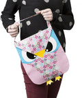 Person holding an owl-shaped, colorful bag with a patchwork pattern and a strap.