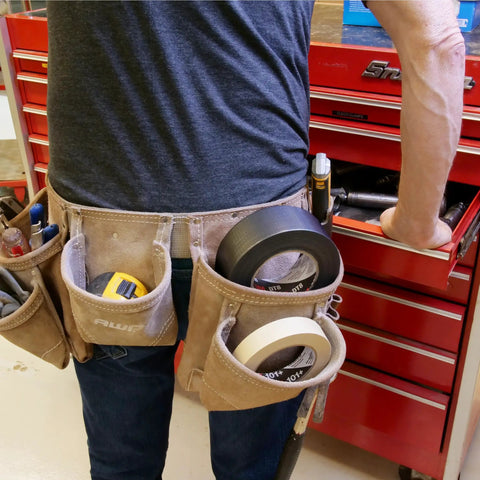 Industrial Strength Black Duct Tape For Patch Jobs And Everyday Fixes in a tool belt next to red toolbox in workshop.