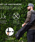Man carrying Two Person Indoor Outdoor Hammock With Steel Stand Cozy Brazilian Gathered End Style Cotton Bed For A Cocoon Vibe Carrying Bag Included Blue Green Stripes.