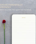 Minimalist lined memo pad with gold foil accents, eco friendly label, next to a red flower. Part of Executive Desk Notepads Bundle For Professionals, Minimalist Lined Memo Pads With Gold Foil Accents, 3 Pack, 225 Sheets Total, Each 6.3 By 3.9 Inches, 80 GSM, Eco Friendly And FSC Certified, Boss Level Office Must Have.
