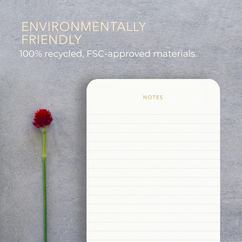 Minimalist lined memo pad with gold foil accents, eco friendly label, next to a red flower. Part of Executive Desk Notepads Bundle For Professionals, Minimalist Lined Memo Pads With Gold Foil Accents, 3 Pack, 225 Sheets Total, Each 6.3 By 3.9 Inches, 80 GSM, Eco Friendly And FSC Certified, Boss Level Office Must Have.