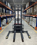 Heavy Duty Electric Straddle Stacker 3300 Lb Capacity in warehouse aisle with pallets stacked on shelves.