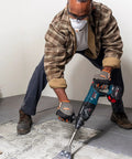Worker using 5 In. By 11 In. SDS-Plus Bulldog Floor Scraper With Durable Steel Blade for tile removal, showcasing long 11 in. shank.