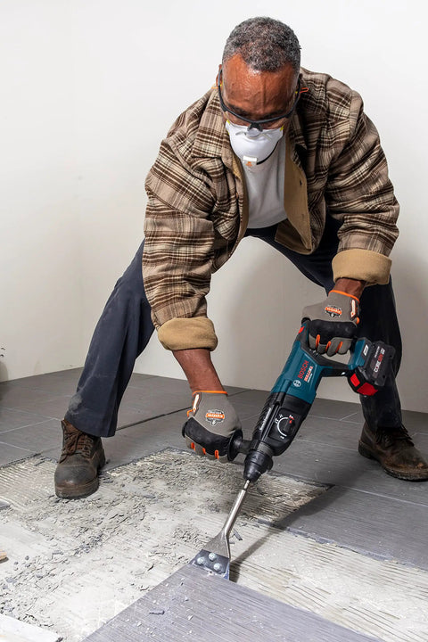 Worker using 5 In. By 11 In. SDS-Plus Bulldog Floor Scraper With Durable Steel Blade for tile removal, showcasing long 11 in. shank.