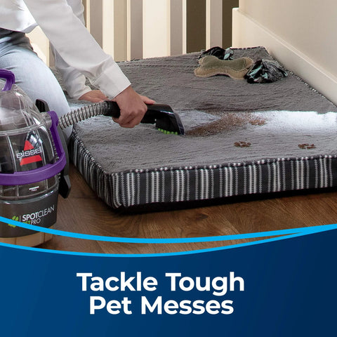 Side view of a Bissell 3-inch Tough Stain Tool attached to a carpet and upholstery cleaner, cleaning a pet bed.