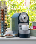 Capsule Spinning Carousel Holder For Espresso Pods next to a coffee machine on a kitchen counter.