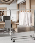 Sturdy Workhorse Commercial Grade Garment Rack With Heavy Duty Steel Construction Extends From 50 To 75 Inches Holds Up To 250 Lbs Chrome Finish Adjustable Hanging Rod For Home Office Or Studio Use in an office setting with shirts hanging.