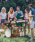 Group enjoying barbecue with All Weather Outdoor Grill Table On Wheels For Patio Garden And Camping Heavy Duty Movable BBQ Prep Cart Rust Proof Weather Resistant Kitchen Stand For Parties Barbecues And Pizza Oven Stand outdoors