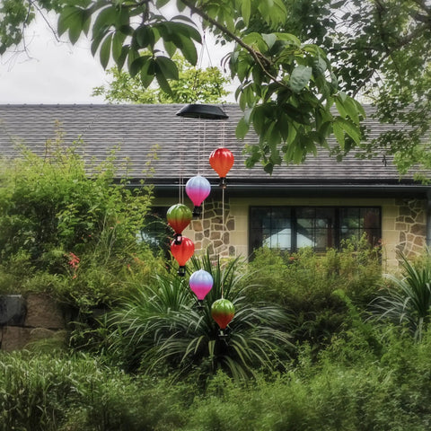 Solar Hot Air Balloon Lantern And Wind Chimes For Garden Outdoor Hanging Lights, colorful LEDs, hanging in lush garden
