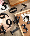 10 Pack Self Adhesive House Numbers 0 To 9 Black 4 By 2.5 Inch No Fuss Easy Peel And Stick Durable Vinyl For Mailboxes Doors Apartments Offices Hotels And Street Address Signs displayed on wooden surfaces with photo frames and newspaper.