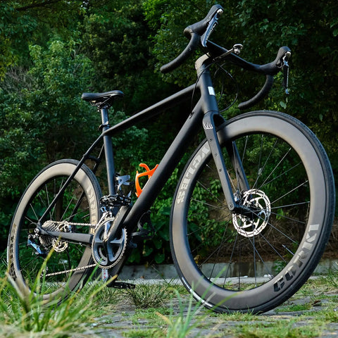Side view of a road bike with Carbon Fiber Road Wheel Set 700C With 60mm Deep Tarmac Series Aero Wheels in a natural setting.