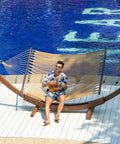Person relaxing on Caribbean Rope Hammock 10.5 Ft Double Outdoor Hammock With Spreader Bars Hand Woven Polyester by poolside