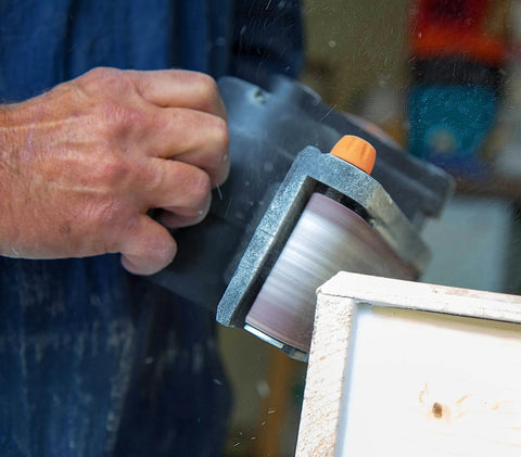 Go-To Corded Belt Sander With Dust Bag, 7 Amp Motor, 3 Inch By 21 Inch Belt in use on wooden surface, close-up view
