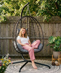 Hanging Egg Chair With Stand For Indoor And Outdoor Relaxation Cozy Wicker Hammock Lounge Chair With Cushion in a garden.