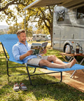 Man relaxing on Folding Chaise Lounge Chair For Poolside Sunbathing And Outdoor Relaxation With Adjustable Backrest near camper