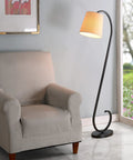 Oil Rubbed Bronze Floor Lamp With Elegant Scroll Design beside a beige armchair in a living room setting.