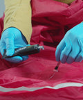 Person using Seam Grip WP Waterproof Sealant and Adhesive for Jackets Tents Tarps Rain Gear and Outdoor Fabric to repair rip.