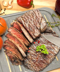 Sliced steak on Air Fry Crisping Basket And Tray Set With Nonstick Bake Pan, surrounded by fresh vegetables on countertop.