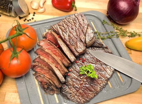 Sliced steak on Air Fry Crisping Basket And Tray Set With Nonstick Bake Pan, surrounded by fresh vegetables on countertop.