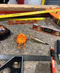 PB008B 8 Ounce Brass Plumb Bob With String on workbench, surrounded by construction tools, showcasing pro grade durable brass.
