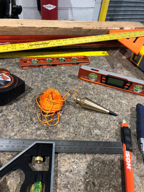 PB008B 8 Ounce Brass Plumb Bob With String on workbench, surrounded by construction tools, showcasing pro grade durable brass.