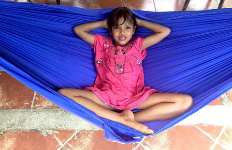 Child relaxing in blue Kid Friendly Camping Hammock For Indoors And Outdoors, Ultra Comfy Hangout Hammock For Kids, on tiled floor.