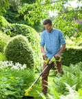 Man using Pro Grade 18 Volt Cordless Grass Trimmer With Dual 2.0 Ah Batteries And Telescopic Handle in a garden.