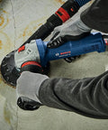Heavy Duty 4 Inch Angle Grinder With Slick Paddle Switch And Lockdown Ergonomic Handle For Tough Metal Cutting And Grinding Duties in use on a concrete surface.